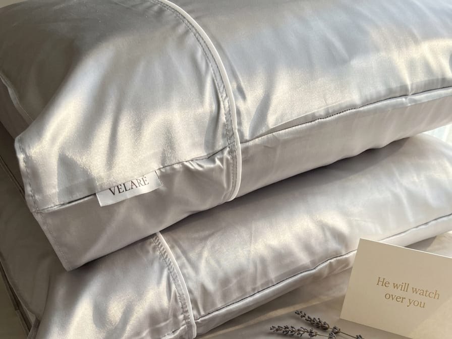 Stacked silver satin VELARÉ pillowcases with visible brand tags